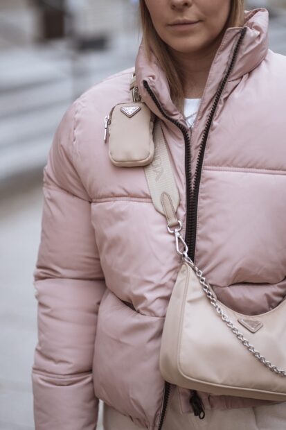 Woman wearing pink Prada jacket with beige Prada bag and pouch on strap