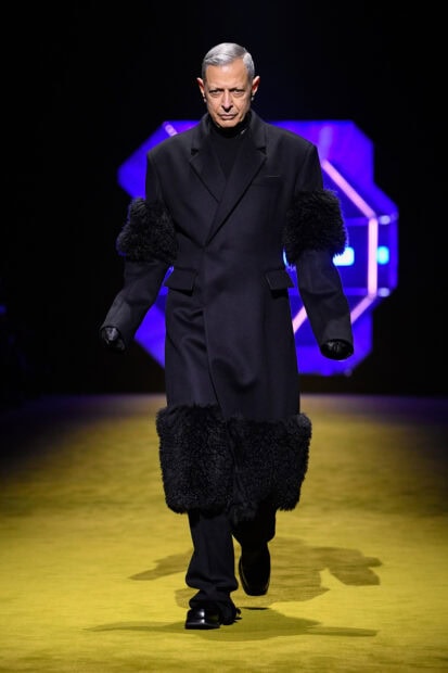 Male model wearing Prada coat with fur details on runway at fashion show