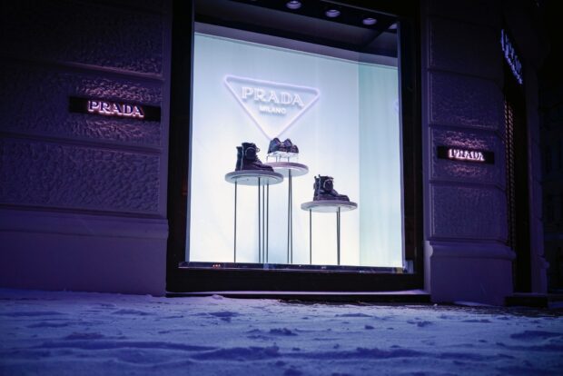Prada display with boots and Prada logo in illuminated store window