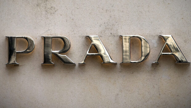 Shiny metal Prada letters on a textured concrete wall