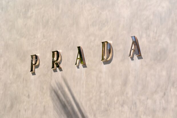 Prada metal letters casting shadows on a smooth wall with the Prada logo displayed clearly