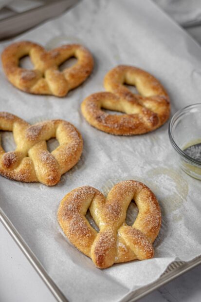 Freshly baked pretzel on baking tray sprinkled with sugar and cinnamon