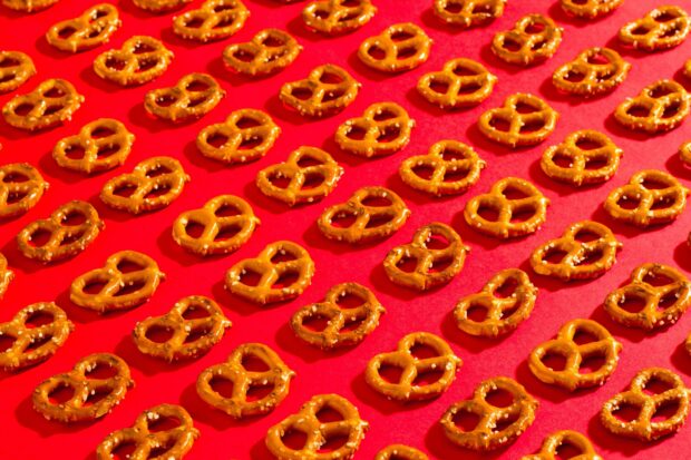Rows of salted pretzel snacks arranged neatly on a bright red surface
