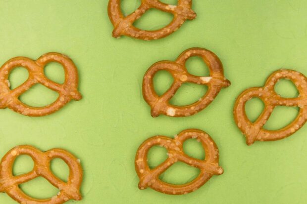 A close up view of crunchy pretzel snacks scattered on a green surface