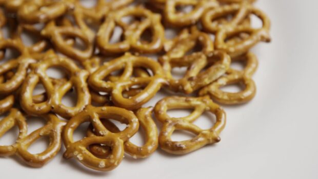 Close up of salt sprinkled pretzel snacks on white surface
