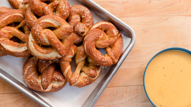 Freshly baked pretzel snacks sprinkled with coarse salt on a tray