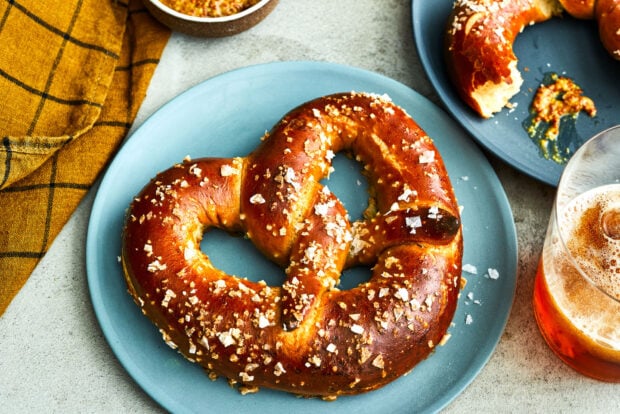 Freshly baked pretzel topped with coarse salt on a blue plate
