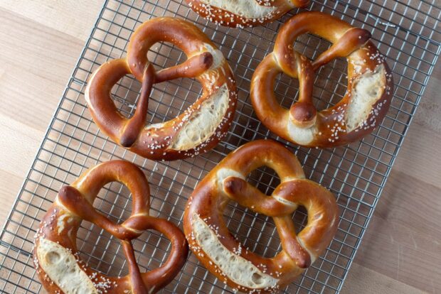 Freshly baked pretzel with coarse salt resting on a cooling rack