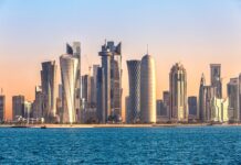 Modern skyline of Qatar with tall buildings and blue sea under clear sky