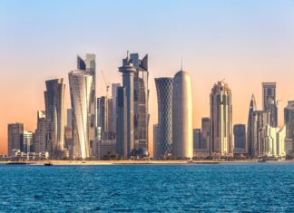 Modern skyline of Qatar with tall buildings and blue sea under clear sky