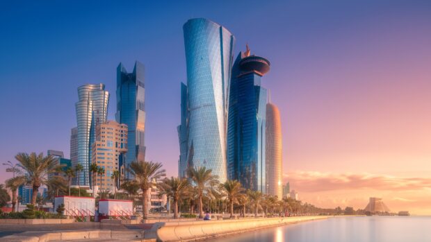 Modern architecture in Qatar city skyline during sunset with waterfront and palm trees