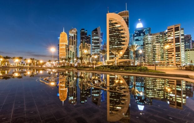 Modern architecture in Qatar city skyline reflecting on water at night with clear sky