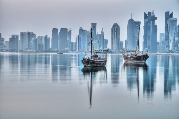 Traditional boats floating in calm waters with modern Qatar skyline in the background