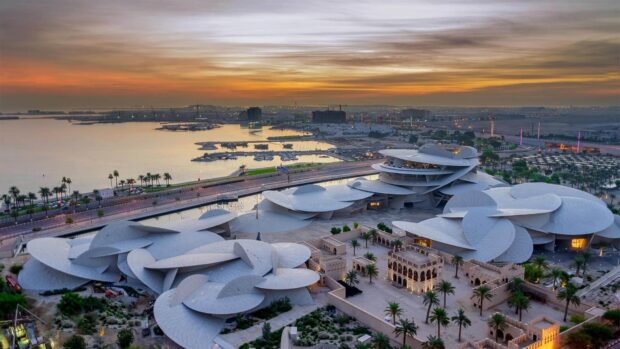 Aerial view of Qatar city architecture at sunset with desert and water in the background