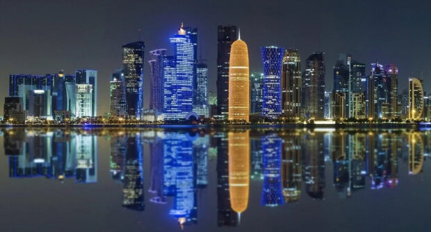 Modern Qatar skyline reflected on calm water at night with vibrant city lights