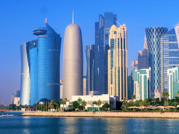 Modern Qatar skyline with futuristic buildings by the waterfront under clear blue sky