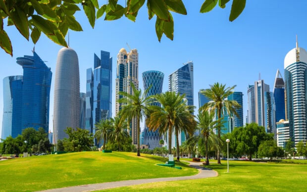 Modern skyscrapers and green park in Qatar cityscape with clear blue sky