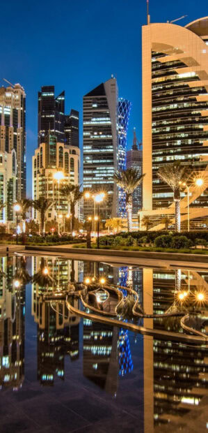 Modern Qatar cityscape at night with illuminated skyscrapers reflection in water