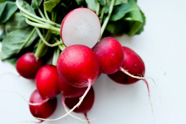 Fresh radish with green leaves on a white surface