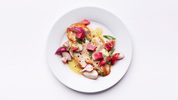 Grilled chicken served with fresh radish and green onions on a white plate