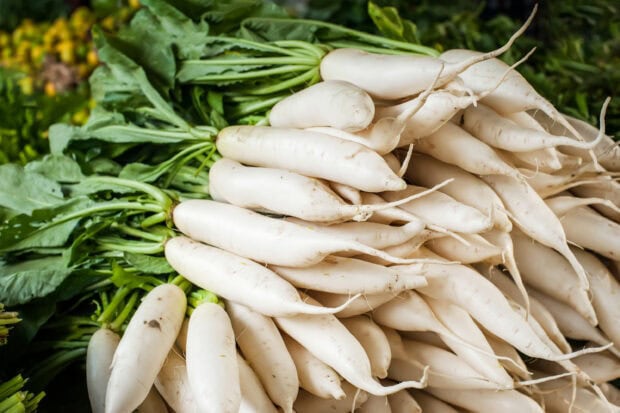 A pile of fresh radish with green leaves on display at the market