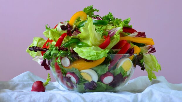 A bowl of fresh radish slices and mixed greens with colorful bell peppers and boiled eggs
