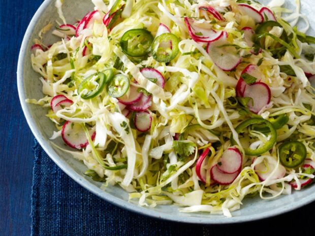 Fresh radish slices mixed with shredded cabbage and green chili peppers in a bowl