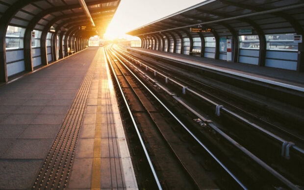 Modern railway station platform with train tracks in the sunset light