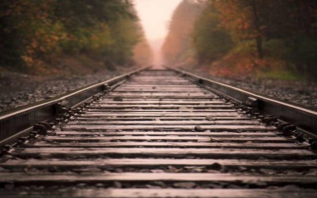 Old railway tracks extending through a forest in autumn with blurred trees in the background