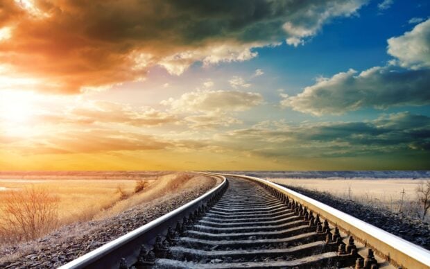 A curved railway track extending into the distance under a dramatic sunset sky