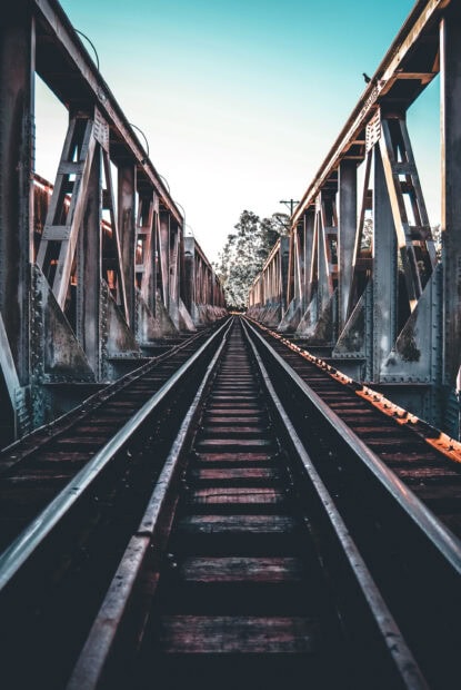 Old railway bridge with tracks extending into the distance surrounded by trees