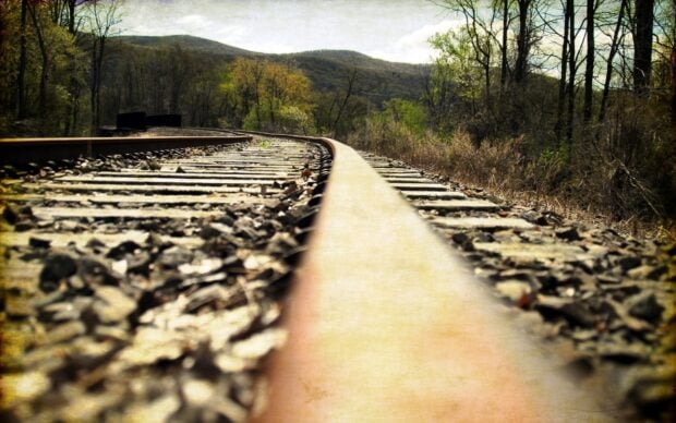 A close up view of railway track stretching into the forested hills