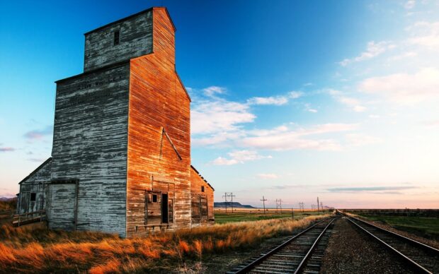 Old wooden railway building beside the railway tracks under a blue sky at sunset