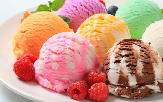Close up of raspberry and colorful ice cream scoops on a white plate
