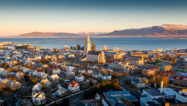 A panoramic view of Reykjavik city with Hallgrimskirkja church and surrounding mountains at sunset