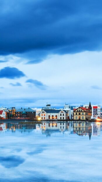 Reykjavik cityscape reflected on calm waters under a cloudy sky