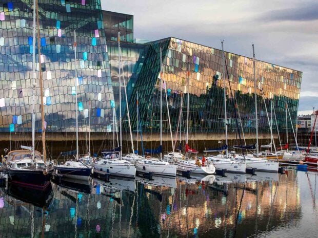 Modern Reykjavik architecture reflecting on the harbor with sailboats docked nearby