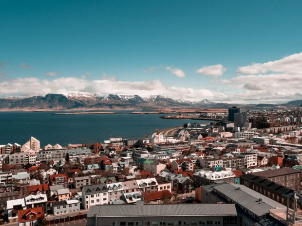 Snow capped mountains surrounding Reykjavik cityscape with colorful houses and blue sky
