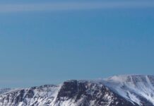 Snow covered Reykjavik cityscape with mountains in the background during twilight