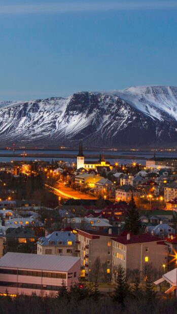 Snow covered Reykjavik cityscape with mountains in the background during twilight