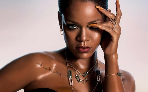 Rihanna showing her tattoo and wearing elegant jewelry with manicured nails