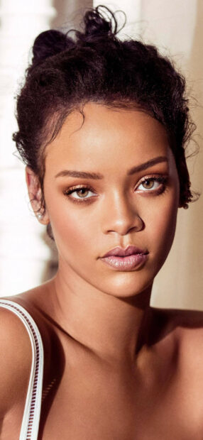 Close up portrait of Rihanna with natural makeup and curly hair pulled up