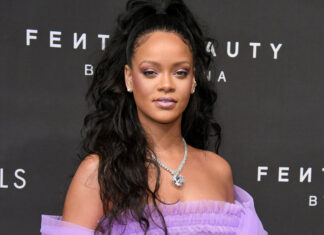 Rihanna wearing a purple dress at a Fenty Beauty event with long curly hair