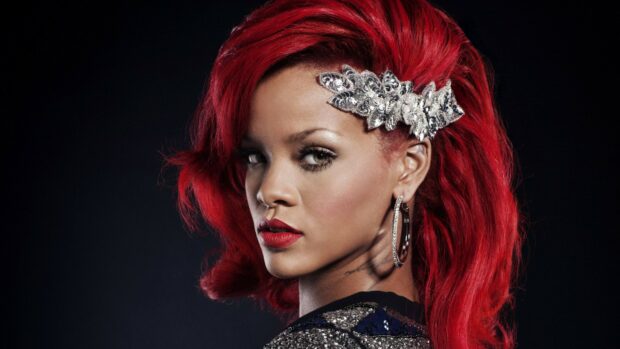 Rihanna with red hair and a decorative hairpiece looking over her shoulder