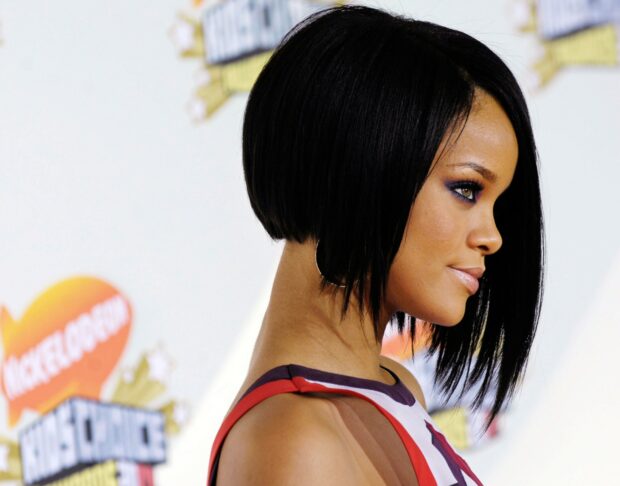 Rihanna with short black hair posing at an award event in a sleeveless dress