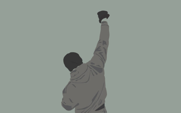 Rocky standing with fist raised in the air wearing a glove on a plain background