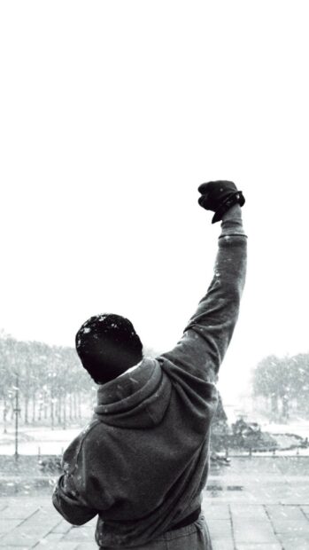 Rocky standing with fist raised in snowy weather wearing winter clothes