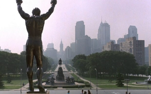 Rocky statue overlooking the city skyline with trees and buildings in the background