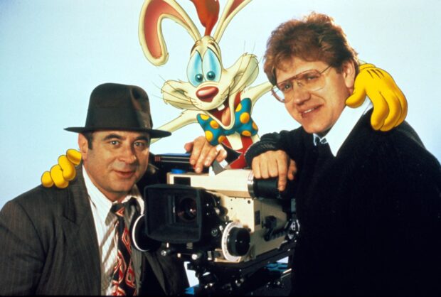 Roger Rabbit standing between two men with a movie camera in a studio setting