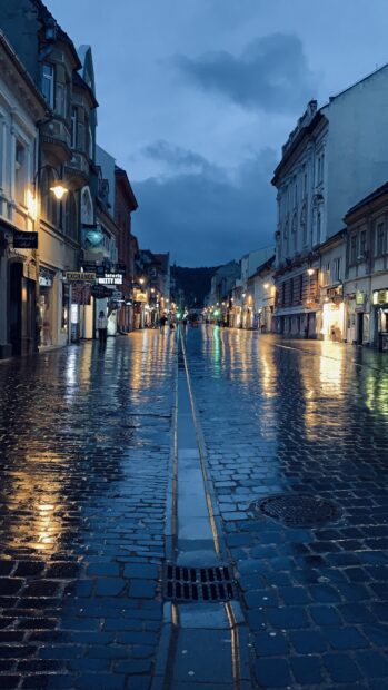 Wet cobblestone street with Romania architecture at dusk in Romania